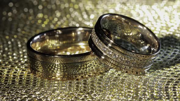 Wedding Gold Rings Lying on Shiny Glossy Surface. Shining with Light. Close-up