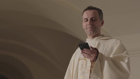Young Pope Using Smartphone and Putting on Black Sunglasses in Church