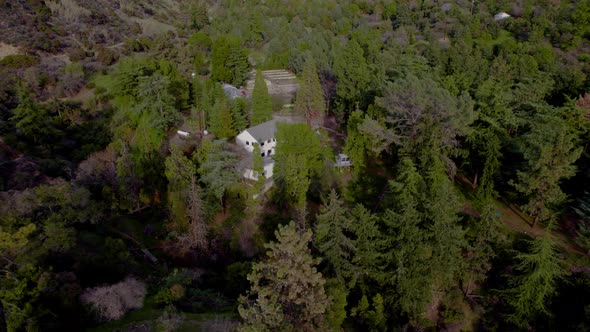 A drone shot of a house in a dense forest in a state park, rural and remote.