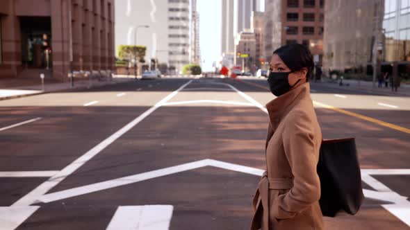 Mixed ethnicity business woman wearing a face mask crosses the street