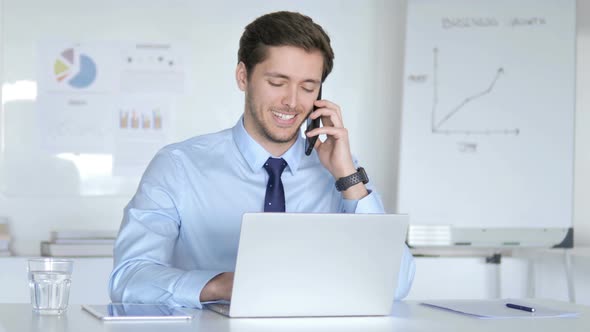 Young Businessman Talking on Phone at Work