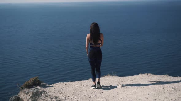 Slow Motion Woman Walks Up to the Edge of the Cliff and Raises Her Hand Up