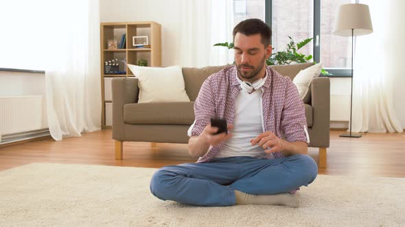 Man in Headphones Meditating in Lotus Pose at Home 