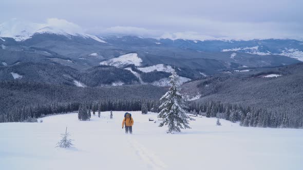 Tourist with a Backpack Climbs the Snowy Slope