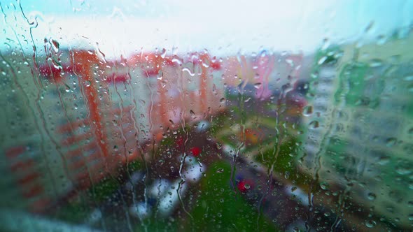 View from inside through the wet window on the city buildings