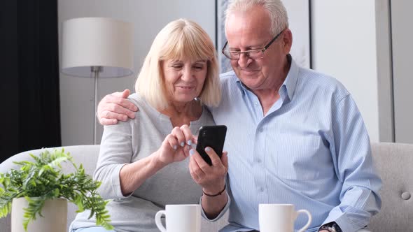 Happy Middleaged Elderly Couple Using Smartphone While Shopping Online