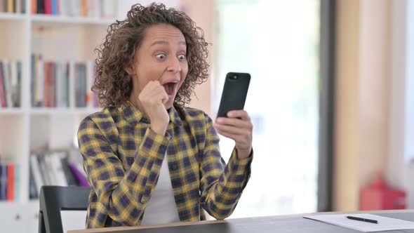 Mixed Race Woman Cheering on Smartphone at Work, Success 