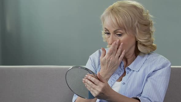 Worried Senior Woman Looking at Her Reflection in Mirror, Plastic Surgery, Aging