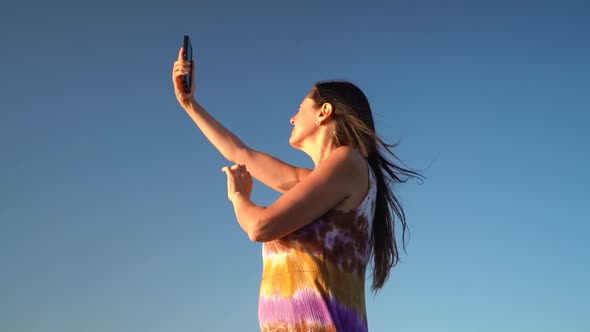 Middle-aged Woman With Mobile Phone Having Network Issues In Blue Sky Background. - low angle