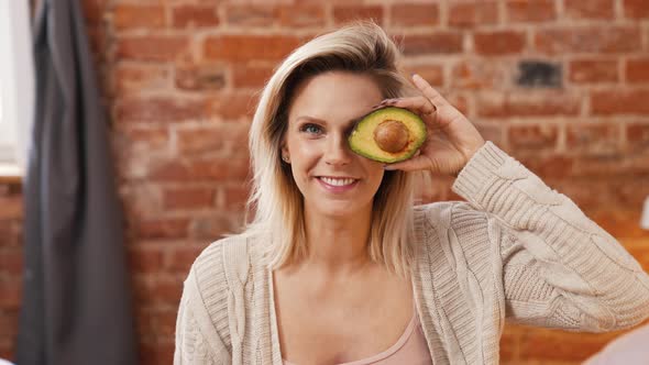 Excited Blond Caucasian Woman with Ripe Delicious Avocado at Home Medium Closeup Healthy Concept