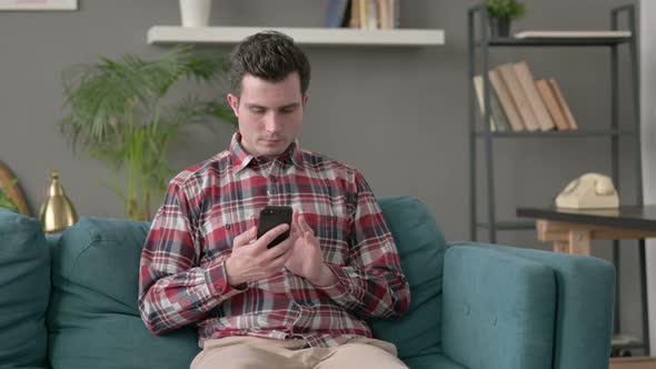 Man Using Smartphone on Sofa