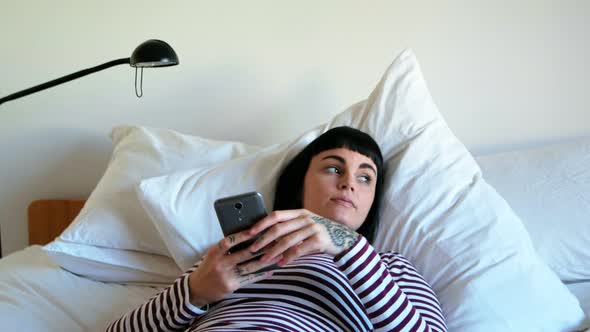 Woman using mobile phone in bedroom 