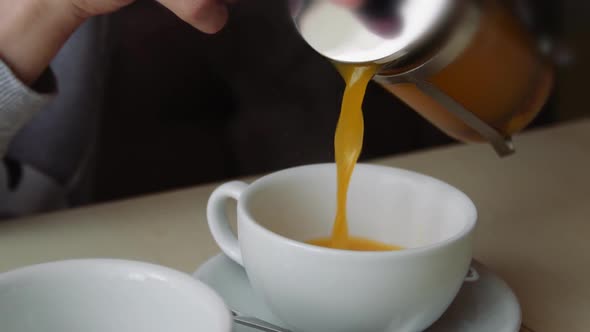 Close-Up Of A Woman Hand Pouring Sea Buckthorn Tea Into A White Сup