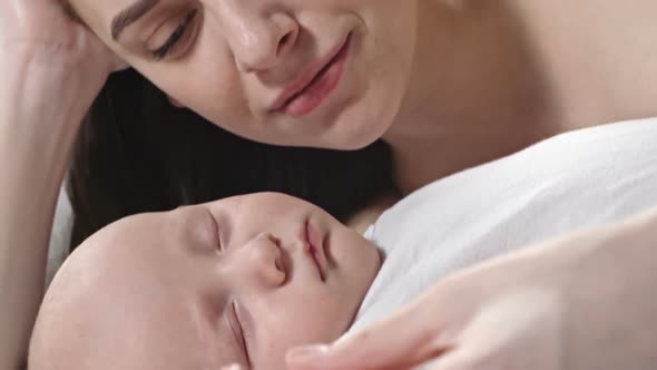 Loving Mother Kissing Sleeping Infant