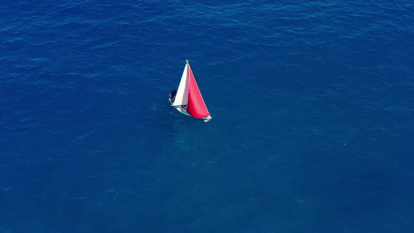 Aerial View. Sailing Yacht with Red Sail in the Open Sea.