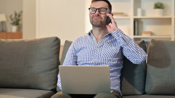 Cheerful Man with Laptop Talking on Smartphone 