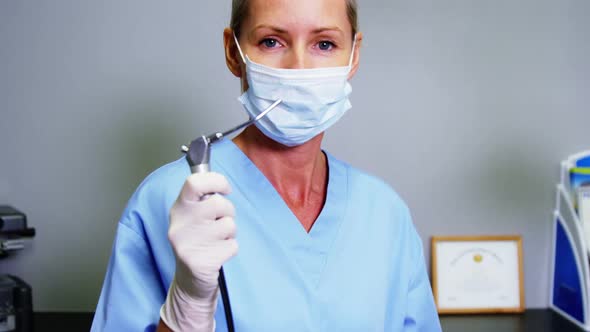 Smiling dental assistant holding dental tool in clinic
