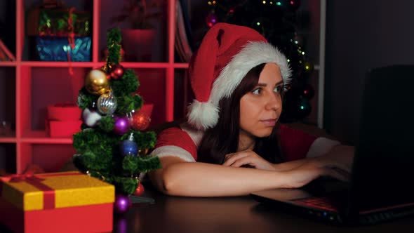 Young Woman in Santa Costume Works at Computer in Office