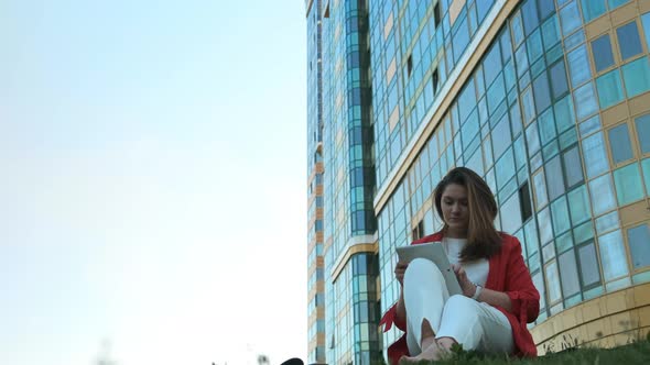 Business Woman Sitting on the Lawn, Against the Background