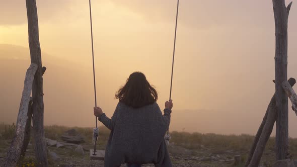 Woman swinging on a swing in Lousa baloico at sunset, Portugal