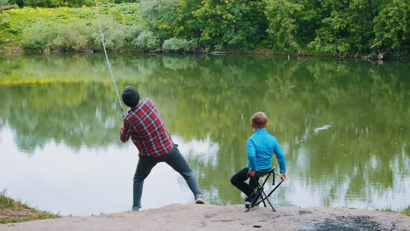 Two Brothers on Fishing - Man Pulling the Rod and His Little Brother Watching Him