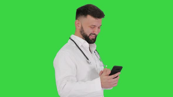 Arab Doctor Walking Using Smartphone and Laughing on a Green Screen, Chroma Key.