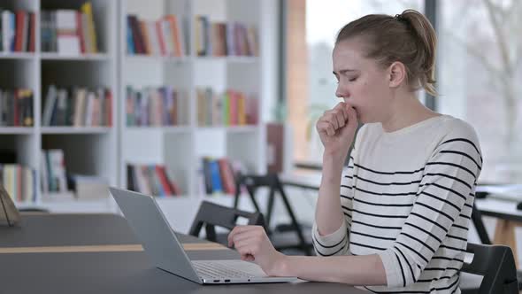Serious Young Woman Using Laptop, Coughing in Library