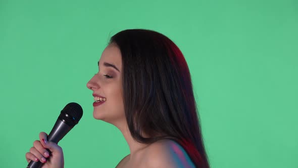 Portrait of Beautiful Young Woman Illuminated By Blue Red Neon Light Sings Song Into Microphone
