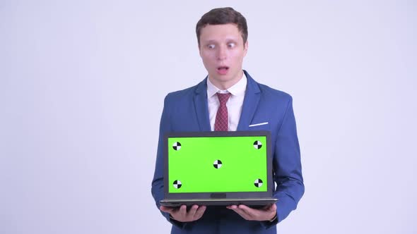 Happy Young Handsome Businessman Showing Laptop and Looking Surprised