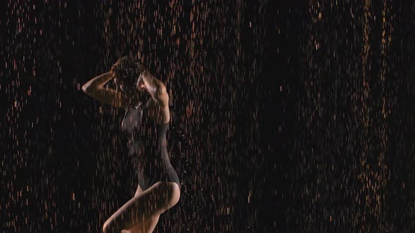 The Gymnast Performs a Wonderful Dance with Elements of Acrobatic Exercises Among Raindrops 