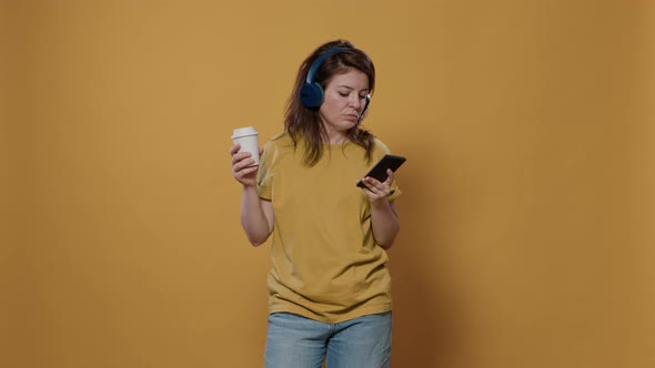 Portrait of Relaxing Woman Holding Recyclable Coffee Cup While Using Smartphone Listening to Music