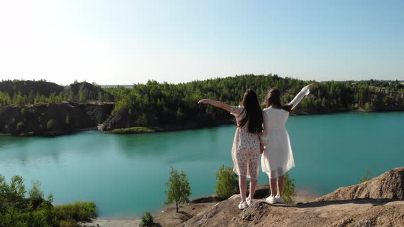 Nice Cinematic Incredible View of Two Women on Top of Mountain Against Background of Blue Lake on