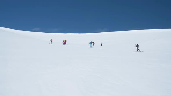 Team of hikers climbing up steep snowy slope in Svalbard, view from bellow