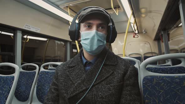 A man rides the subway during a pandemic. Listens to music from the phone.