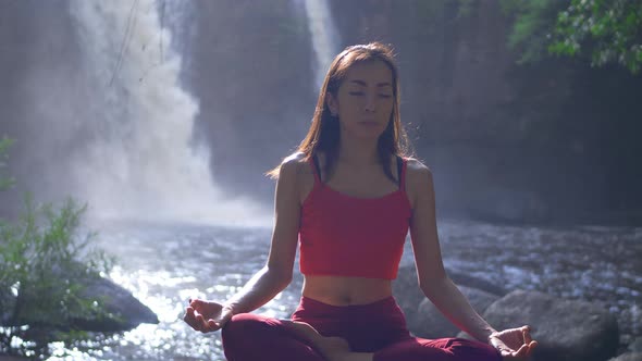 Asian woman practicing or doing yoga at the waterfall