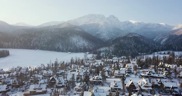 Cinematic view of the mountains and a small town in the snow in winter