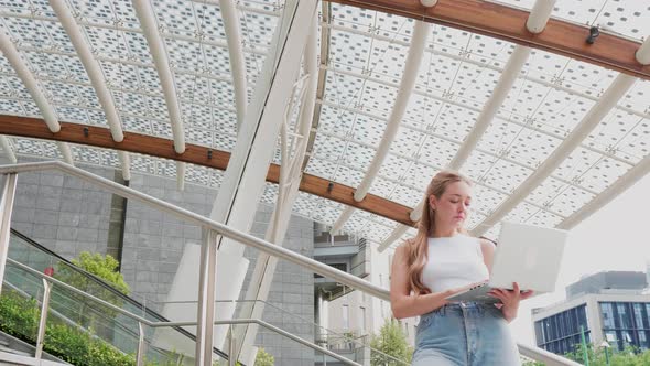 Slow motion young flexible worker outdoor holding computer