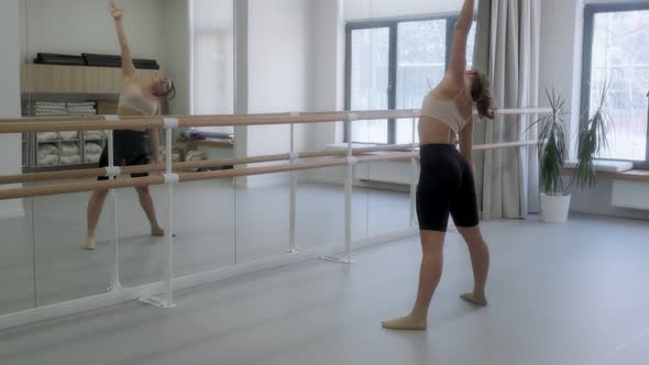 Ballerina rehearsing in the studio in front of a mirror at the white bright dance hall, ballet