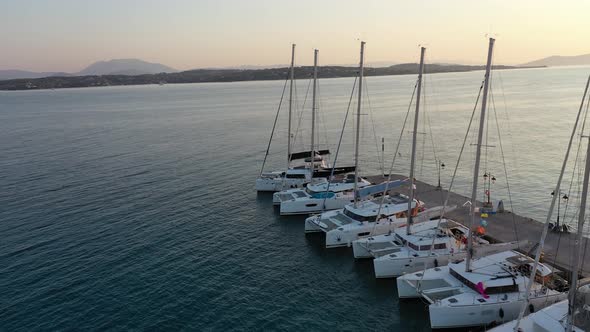 Catamaran and Sail Yachts Anchored at Bay on Deep Blue Sea Water on Sunrise