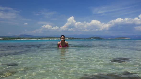 Young girl stand in  water on beach in Halkidiki, Greece in summertime