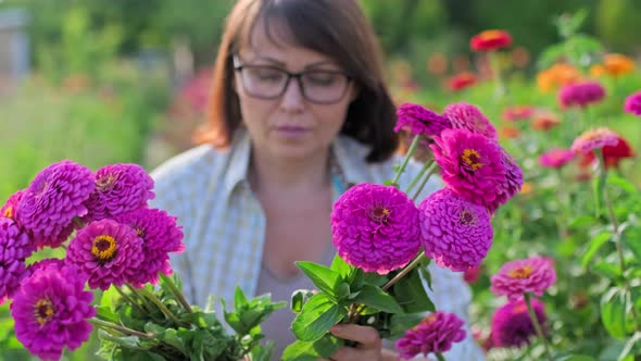 Woman with Fresh Zinnia Flowers Outdoor in Garden with Blooming Flowers