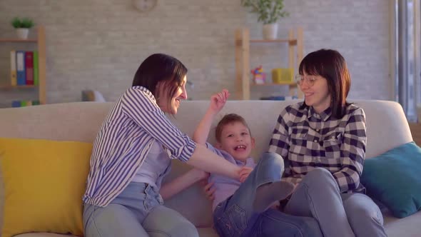 Happy Family Two Young Femals and Little Son on the Couch