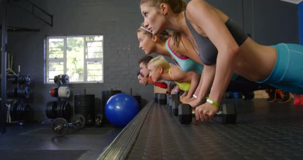 Group of people performing push-up with kettlebell