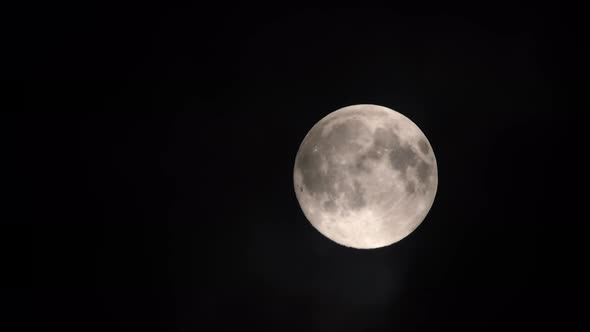 Clouds passing by the full moon, real time shot. Full moon at night with clouds in real time.