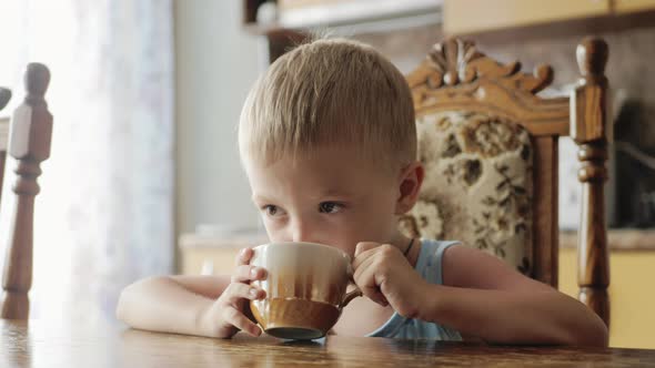 Little Boy is Drinking a Tea at Kitchen Home