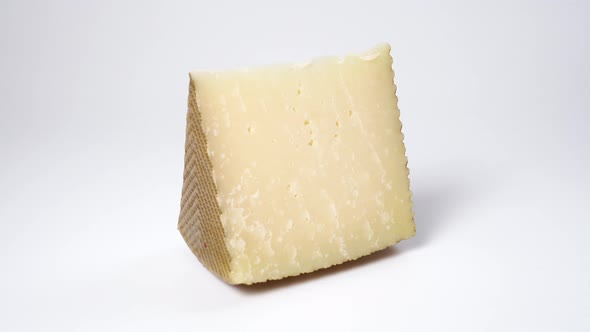 Wedge of old hard cheese on a white surface 