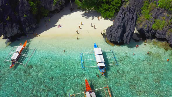 Tourists Enjoy Azure Sea on the Entalula Beach in El Nido, Palawan, Philippines.