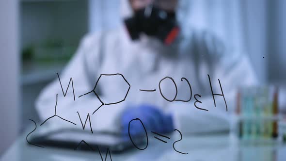 Chemist in Gas Mask Entering Research Results Into Tablet, Formula on Foreground