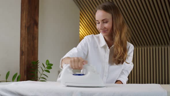 Young Pretty Smiling Woman Irons Clean Underwear at Home