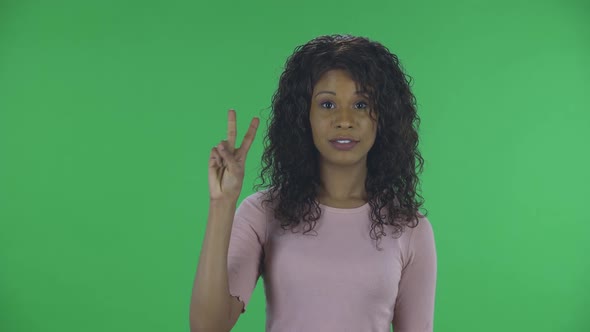 Portrait of Beautiful African American Young Woman Is Looking at Camera and Shows Fist, Then